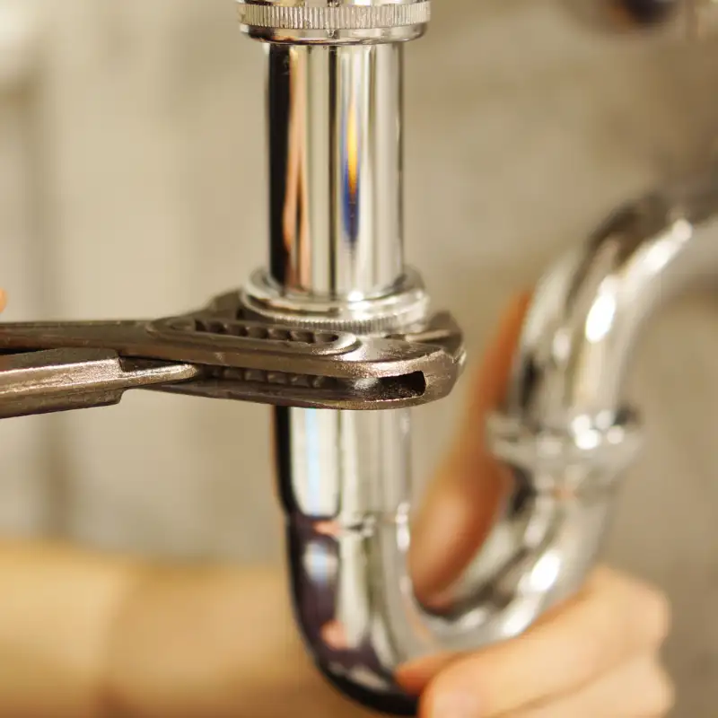 Wrench tightening a chrome sink P-trap